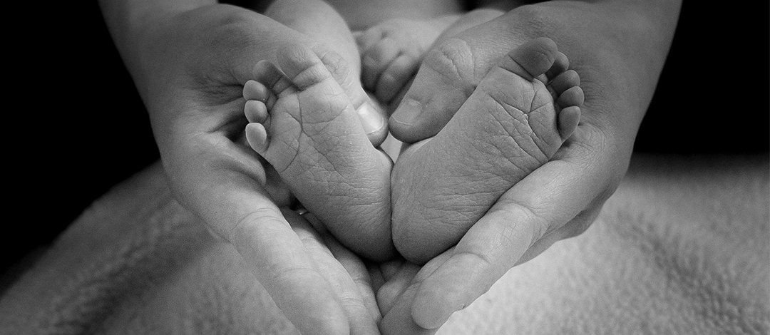 Pieds d'un nourisson dans les main d'un thérapeuthe